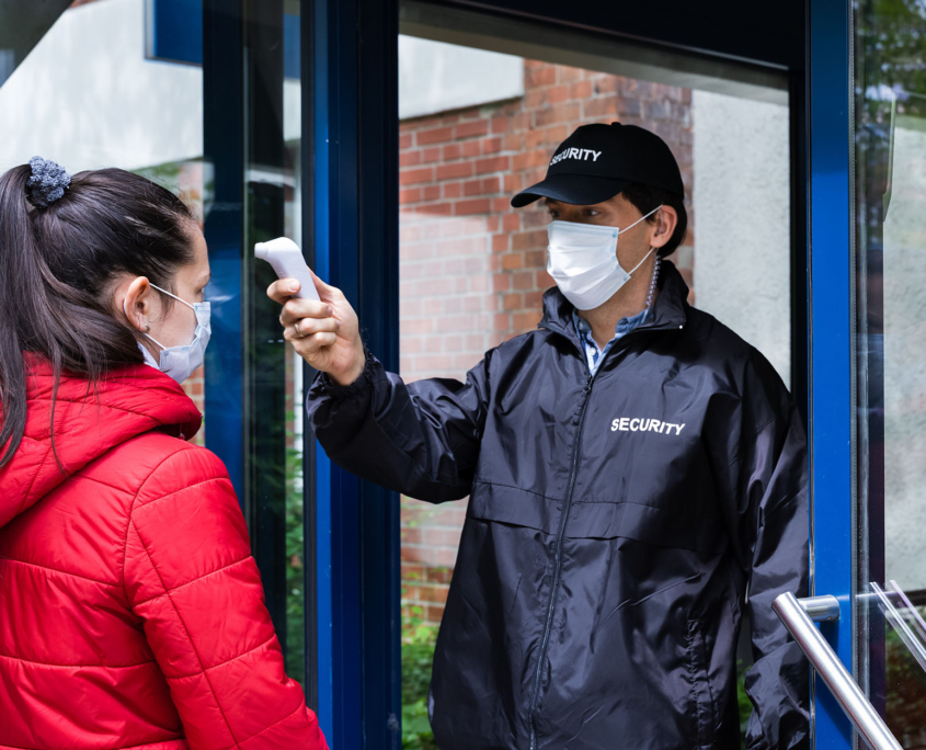 Security guard checking temperature at front entrance of hospital